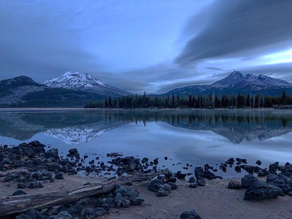 lake with reflections of snow-capped mountains and a forest